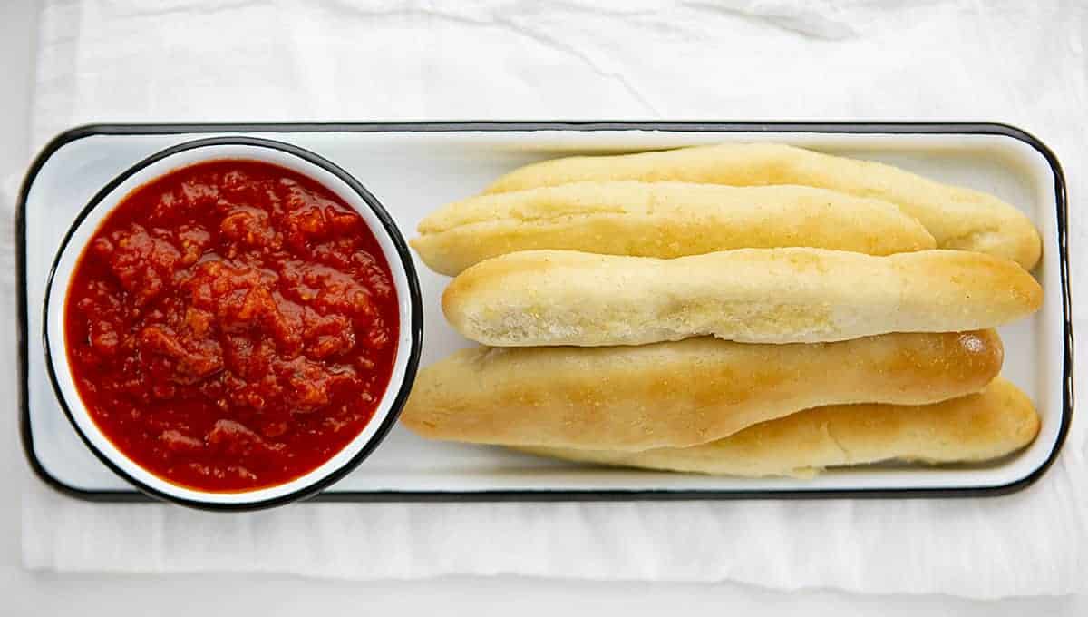 Overhead Image of Garlic Breadsticks Served with Marinara Sauce on White Towel