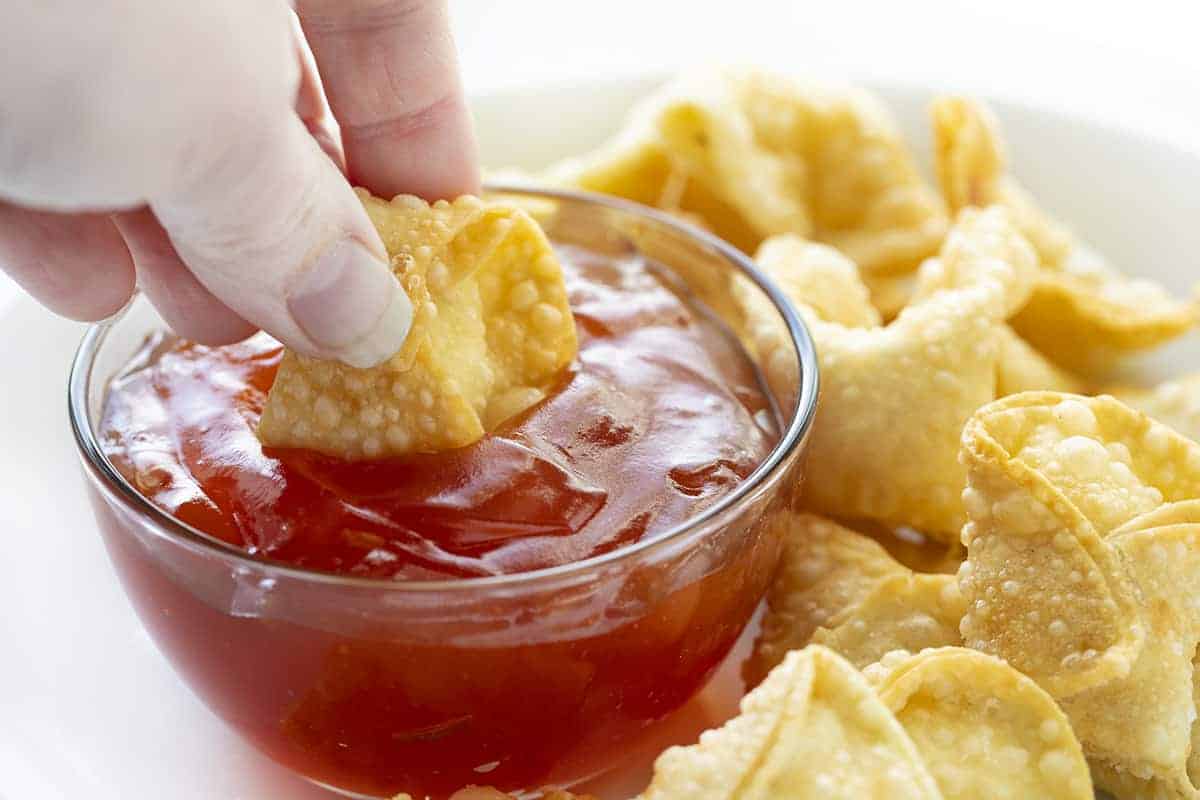 Hand Dipping Homemade Cream Cheese Wonton into Sweet Sour Sauce