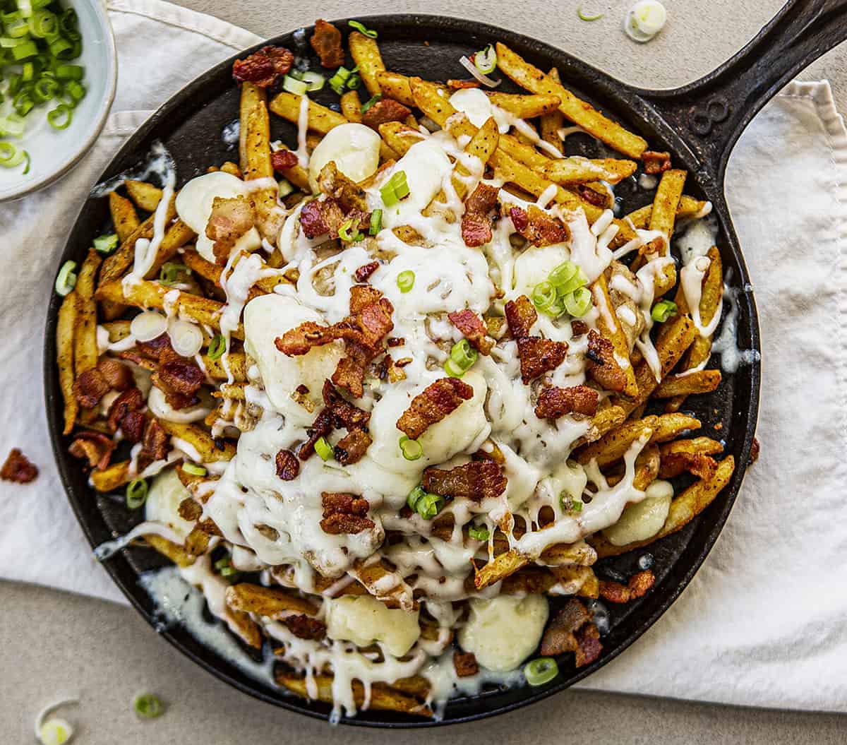 Overhead Image of Poutine with Bacon and Scallions in Bowl in Back