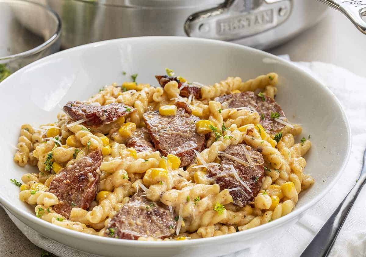 Smoked Sausage Pasta in White Bowl in Front of Hestan Pan