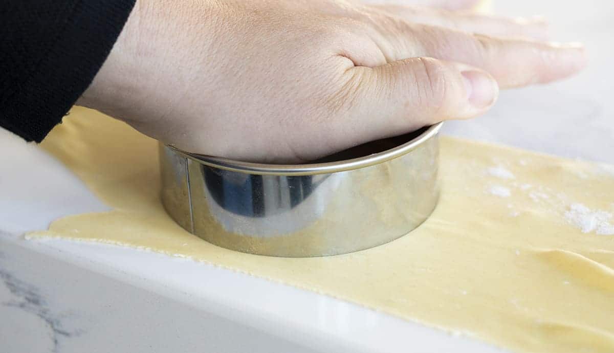 Hand Pressing Round Cookie Cutter into Wonton Wrapper Dough
