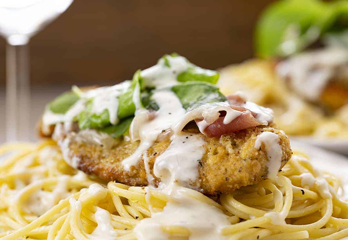 Cheesecake Factory Chicken Bellagio Recipe - Chicken on a Bed of Spaghetti Noodles with Wine Glass in the Back