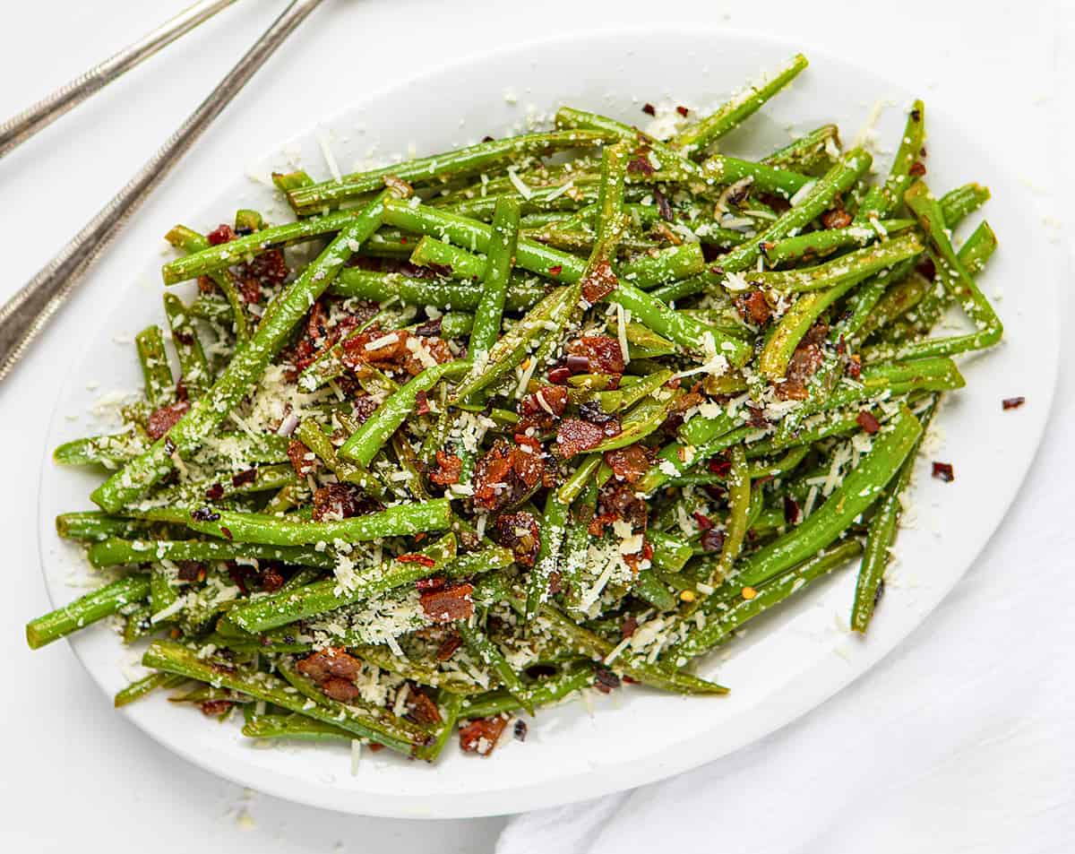 Spicy Green Beans with Bacon Recipe on White Plate with Spoons Next to It