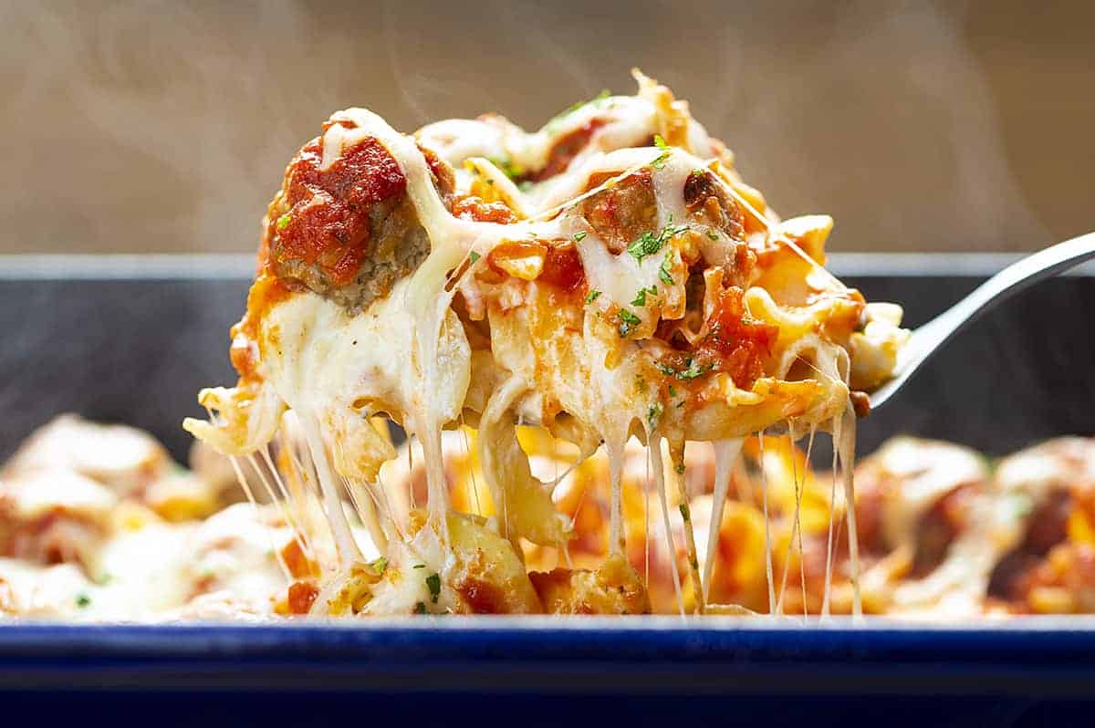 Spatula Picking Up Cheesy Meatball Casserole from Blue 9x13 Pan