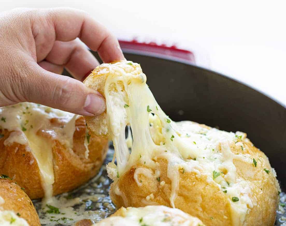 Hand Picking up a Piece of Cheesy Garlic Bread with Cheese Stretching
