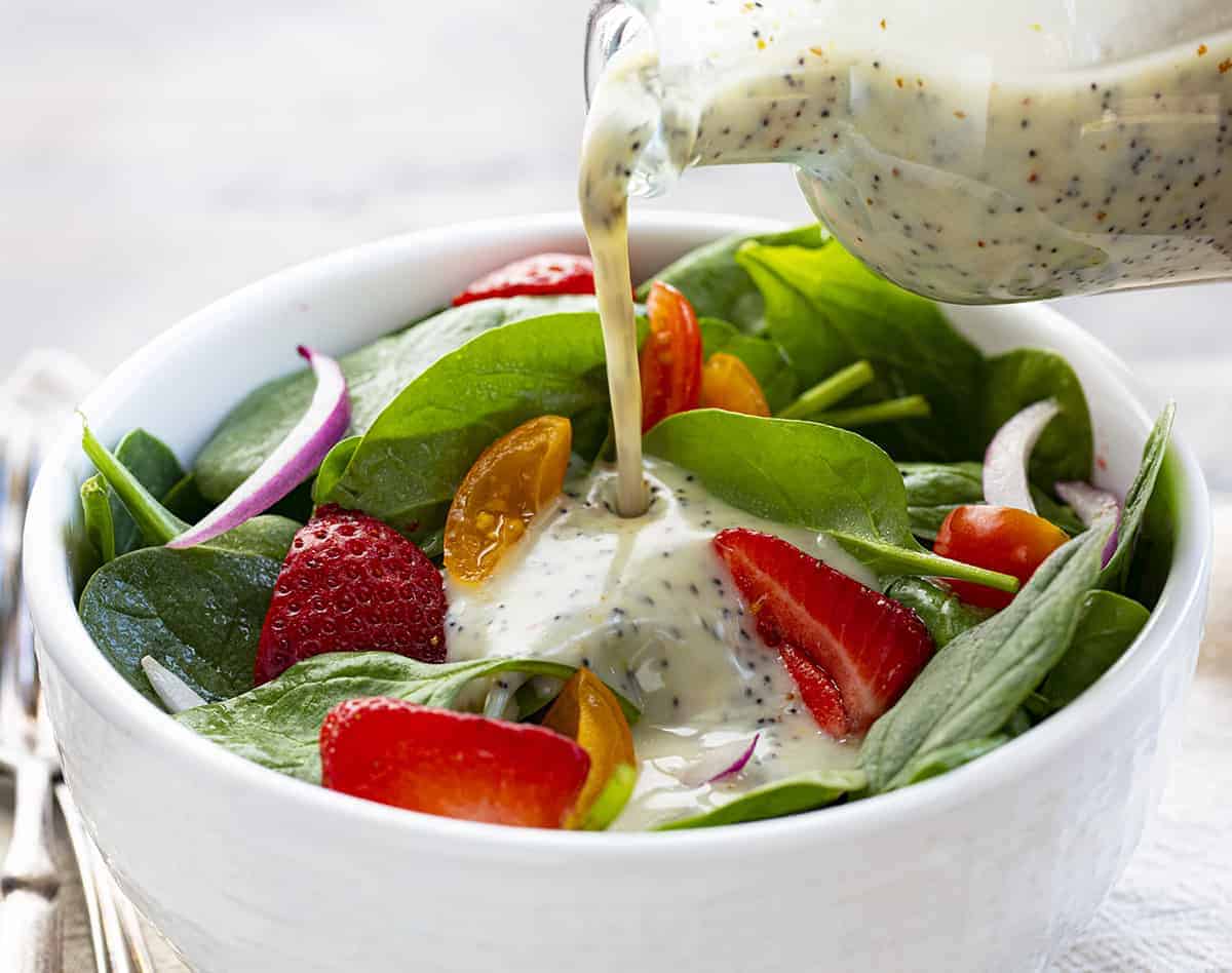 Pouring Poppyseed Dressing over Strawberry Salad