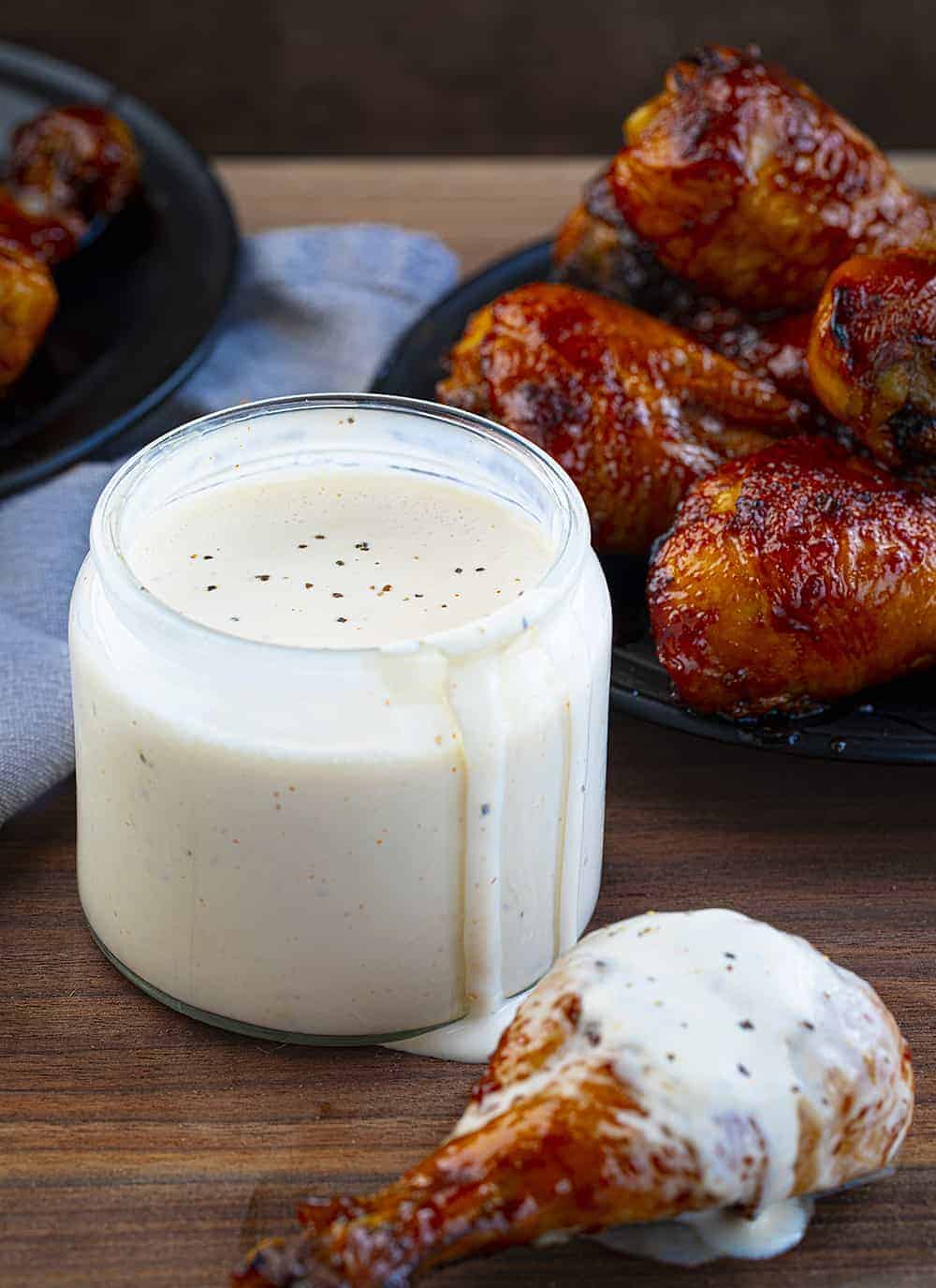 Chicken Sitting Next to Jar of Alabama White Sauce Recipe Spilling Over