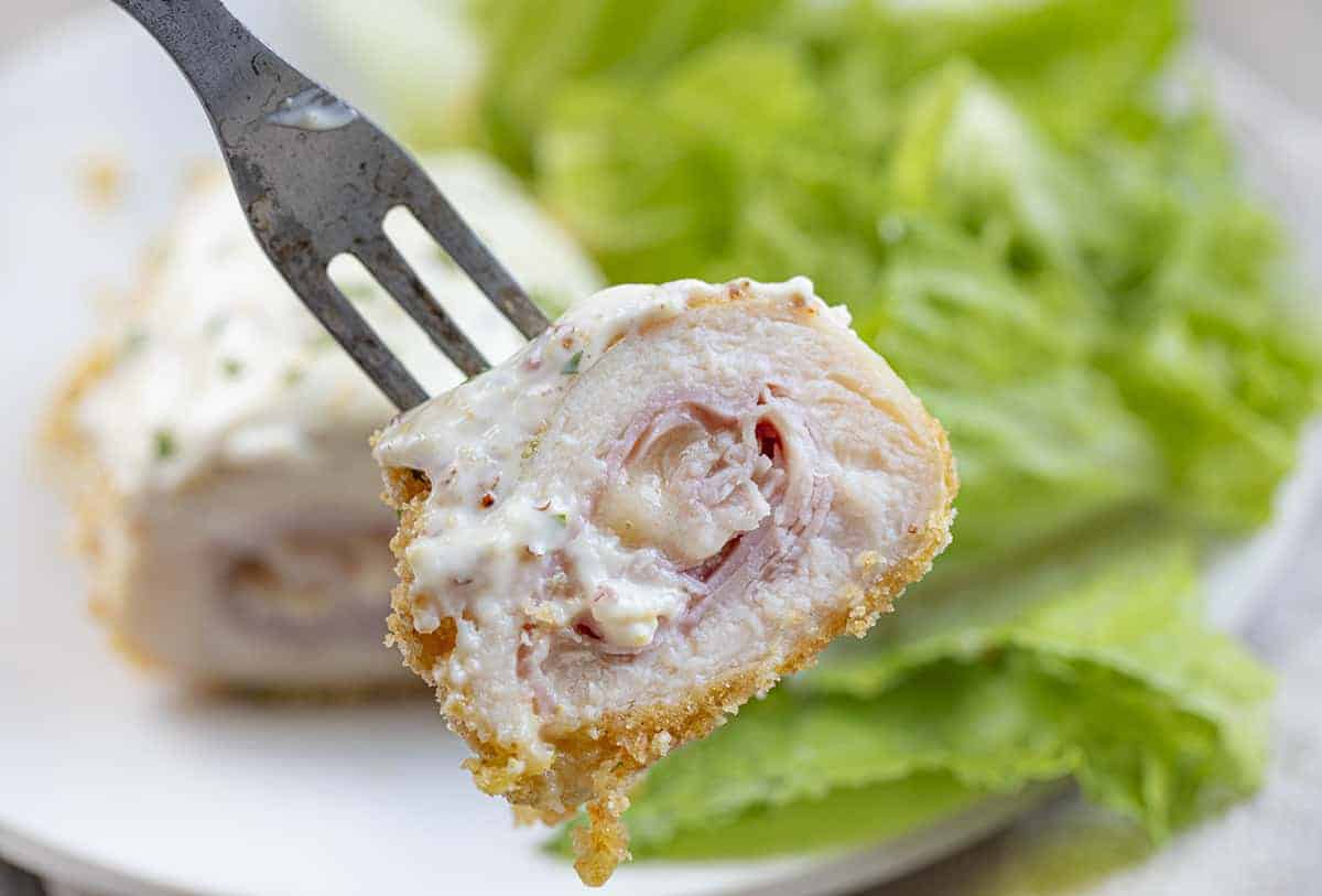 One Bite of Chicken Cordon Bleu on a Fork Showing the Gooey Cheese Inside