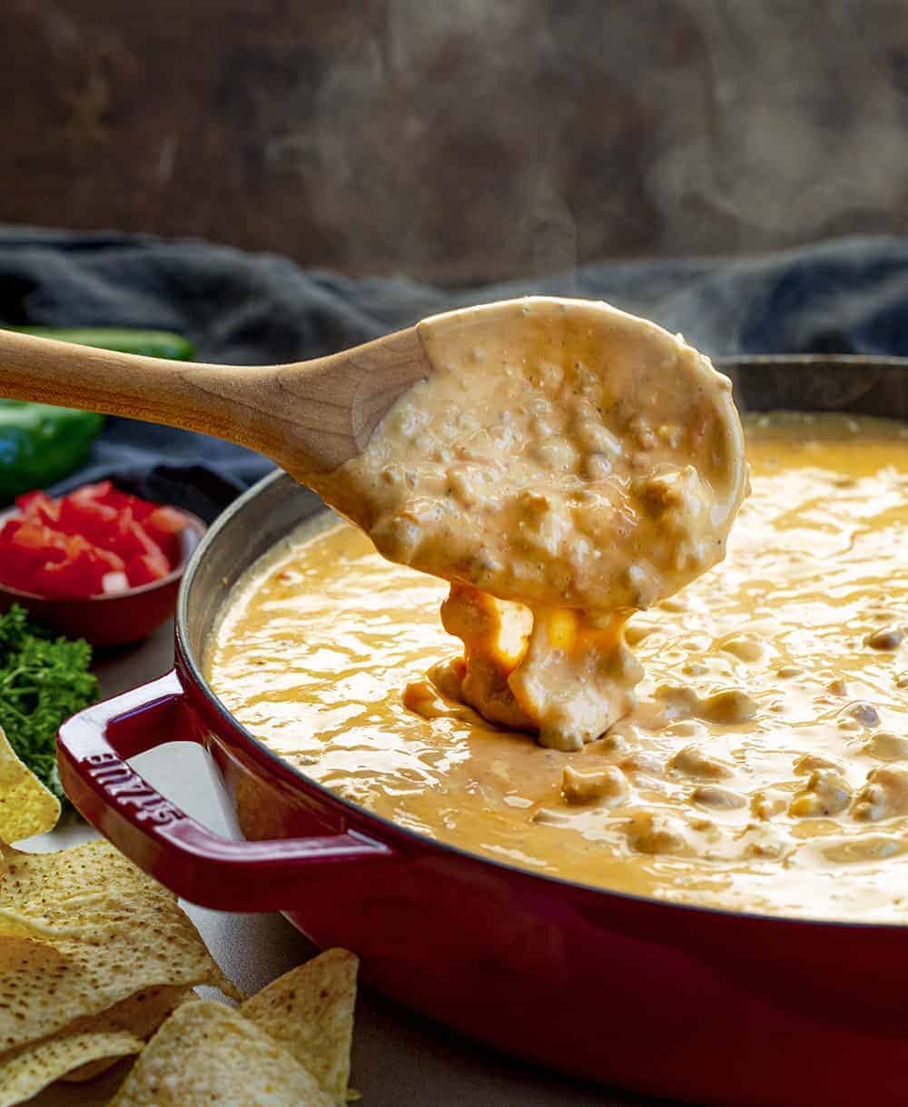 Spoon Picking Up Steaming Queso Dip from Red Skillet