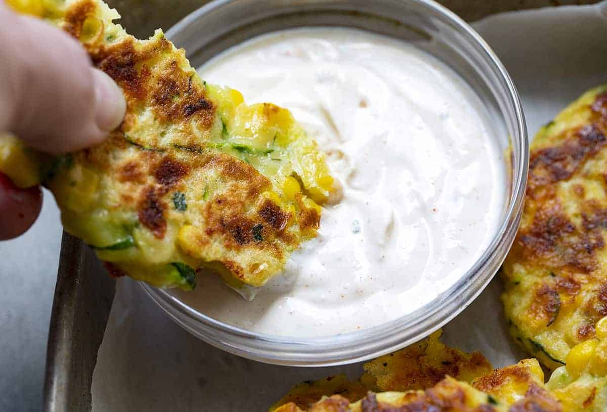 Dipping Zucchini Fritters into Homemade Sauce