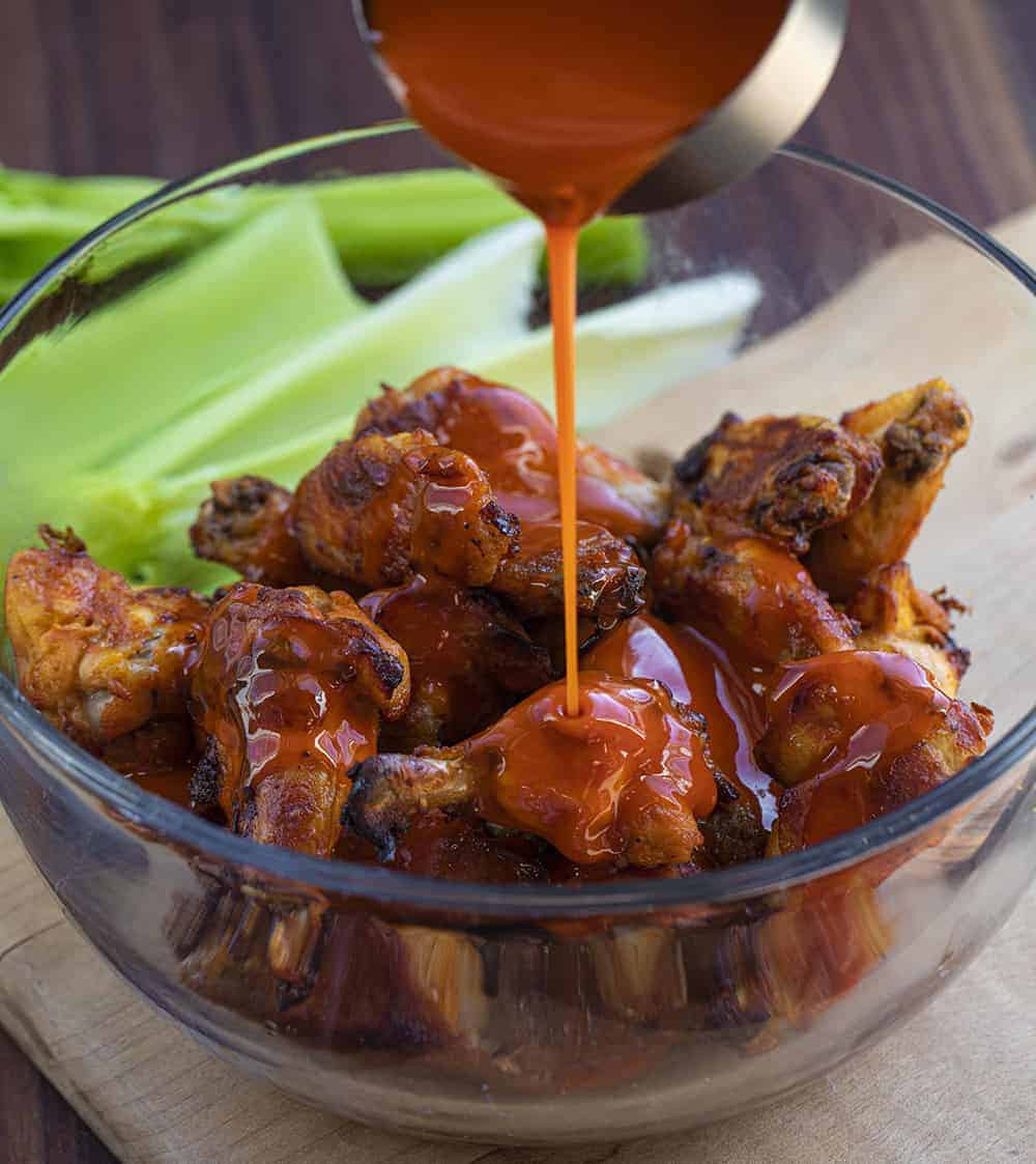 Pouring Buffalo Sauce over Buffalo Chicken Wings