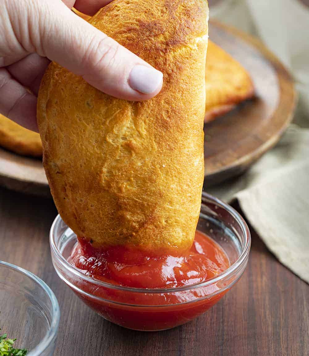 Dipping Air Fryer Cheeseburger Hand Pie into Ketchup