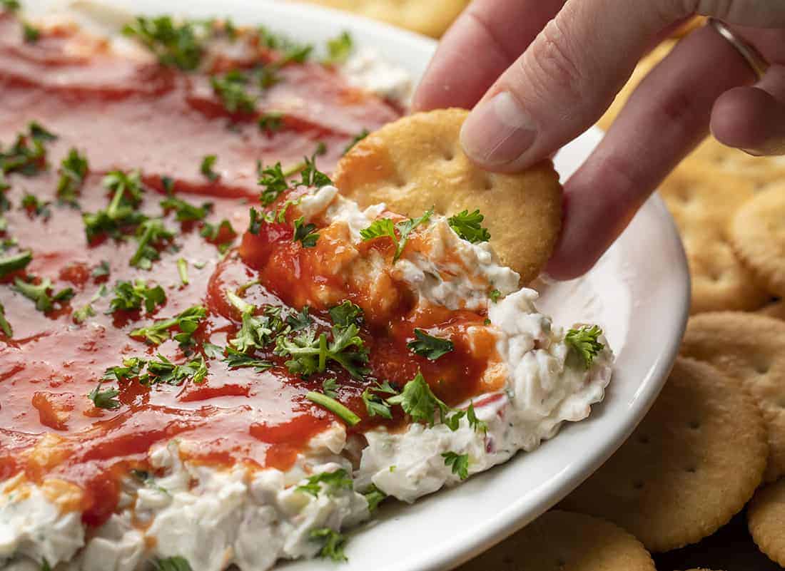 Hand Holding Cracker in Easy Crab Dip Recipe