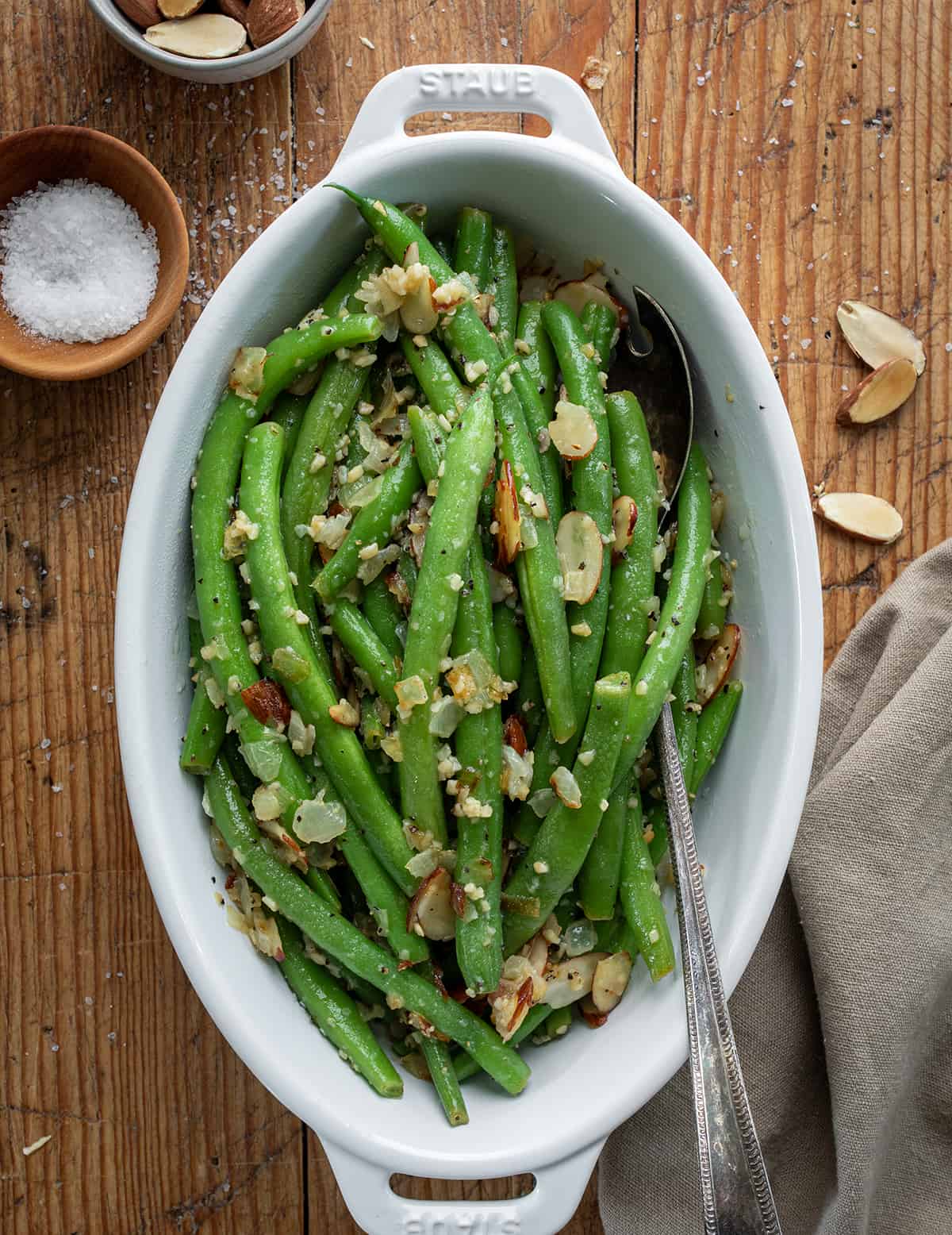 Casserole Dish of Green Beans Almondine on a Wooden Cutting Board. 