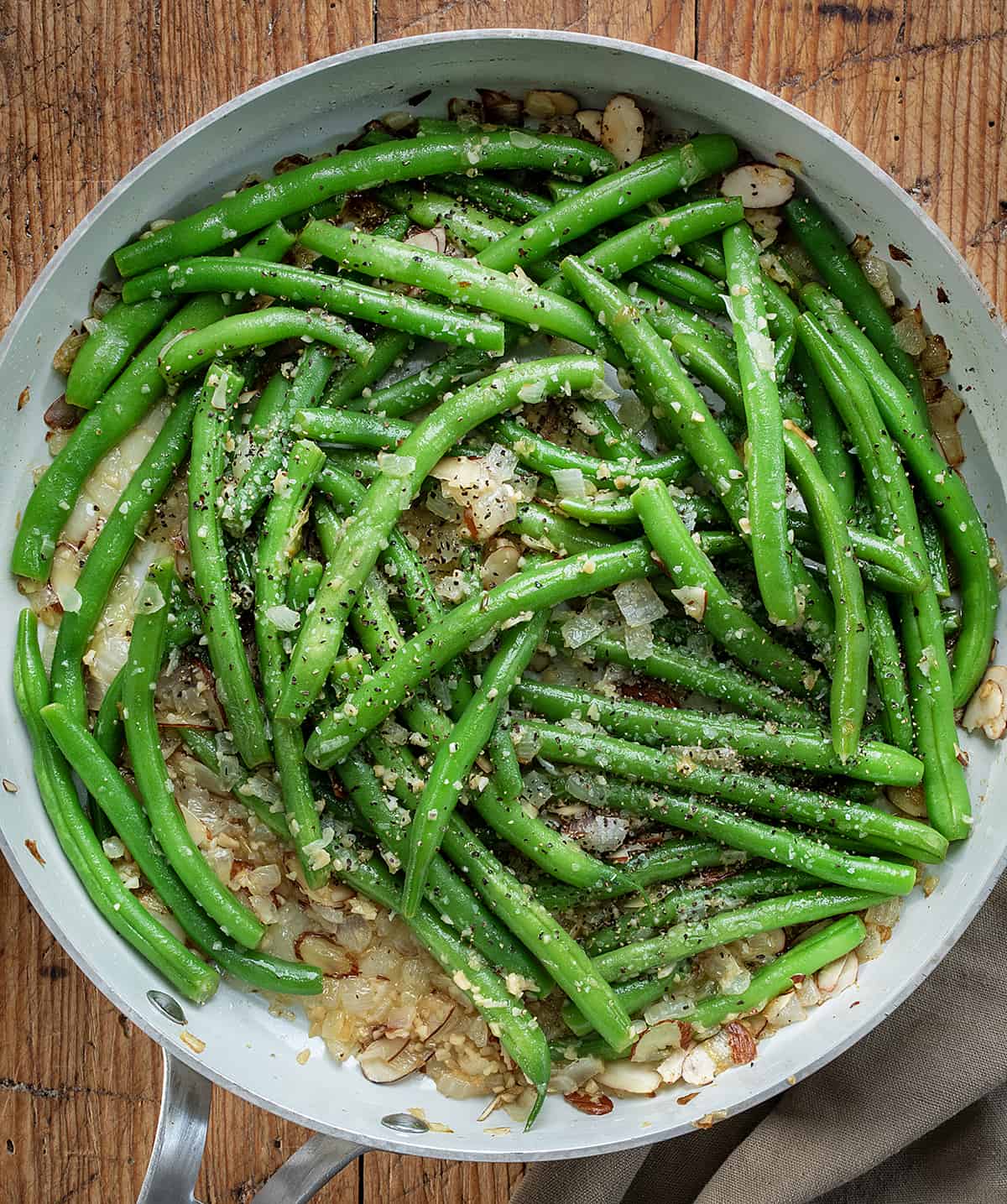 White Pan of Green Beans Almondine on a Wooden Cutting Board.