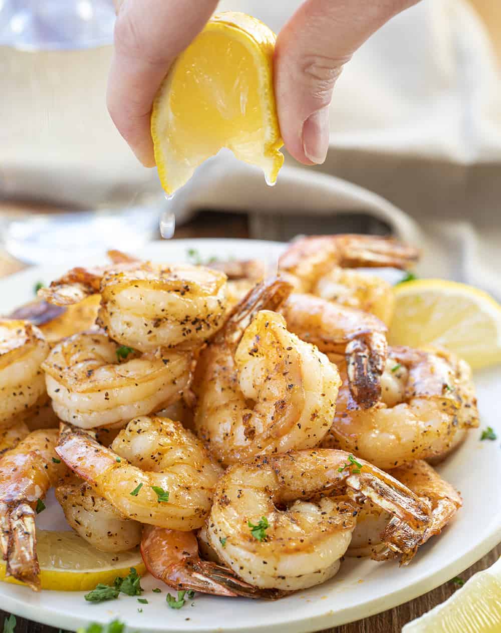 Squeezing Lemon over a Plate of Air Fryer Shrimp.