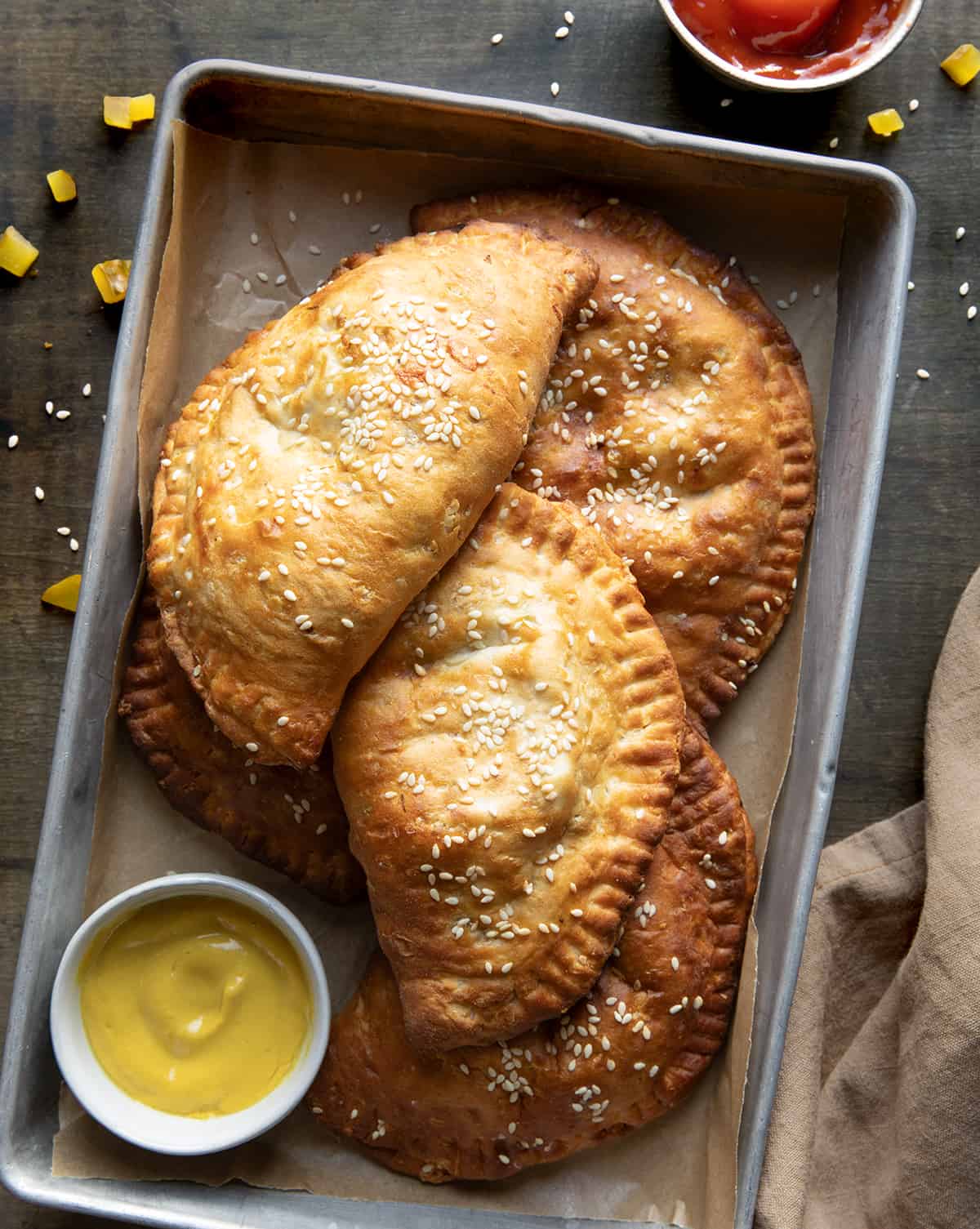 Cheeseburgers Hand Pies in a pan on a table with mustard and ketchup.