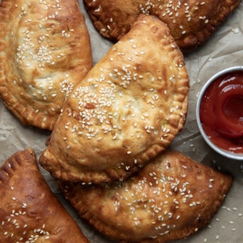 Cheeseburgers Hand Pies on a piece of parchment paper with ketchup.