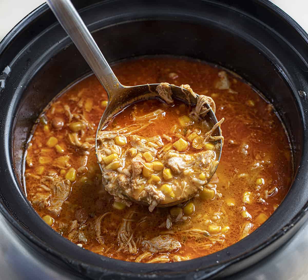Ladle full of Spicy Chipotle Chicken Soup in a Crockpot