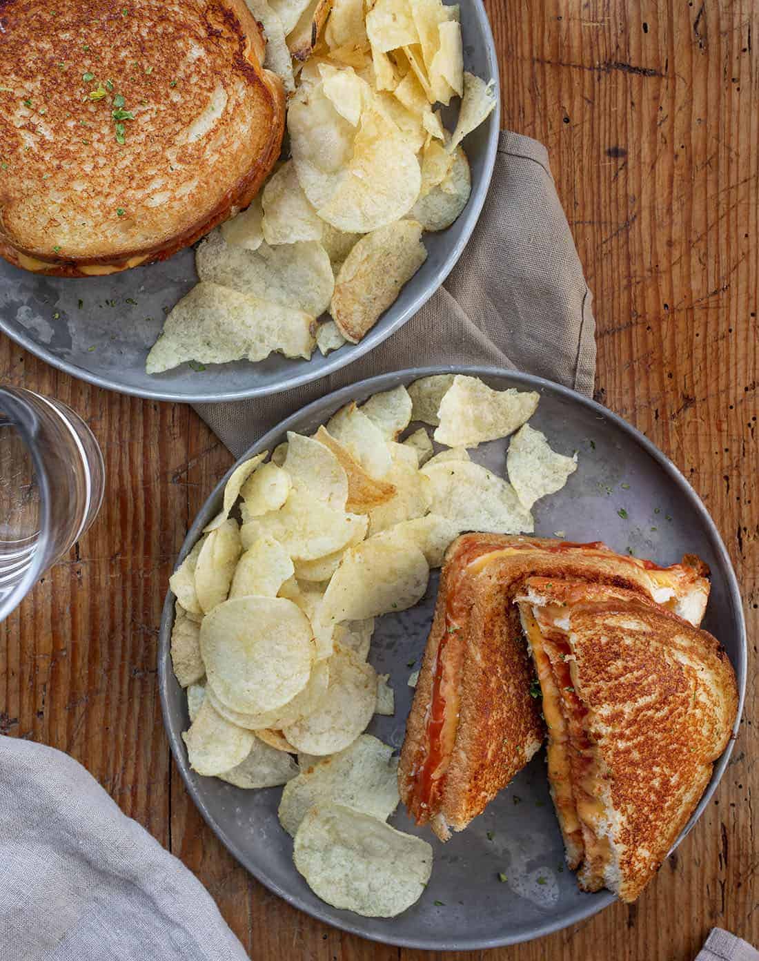 Triple Decker Tomato Grilled Cheese Sandwiches on Plates with Potato Chips from Overhead