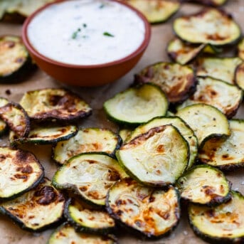 Ranch Zucchini Chips on a Counter Next to Ranch Dressing.