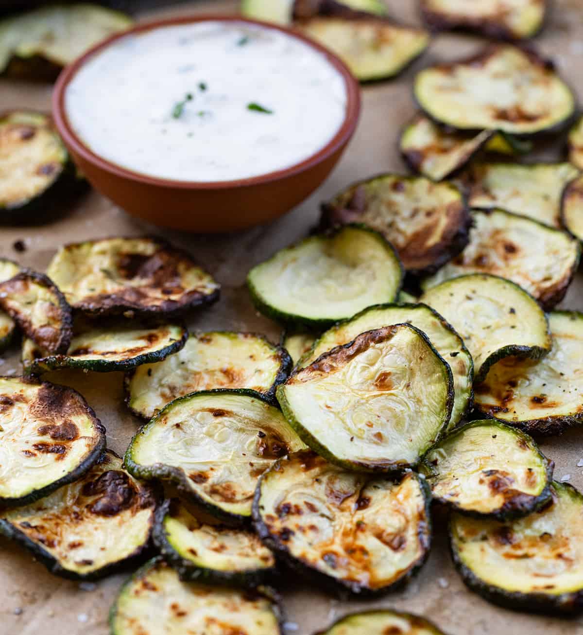 Ranch Zucchini Chips on a Counter Next to Ranch Dressing.