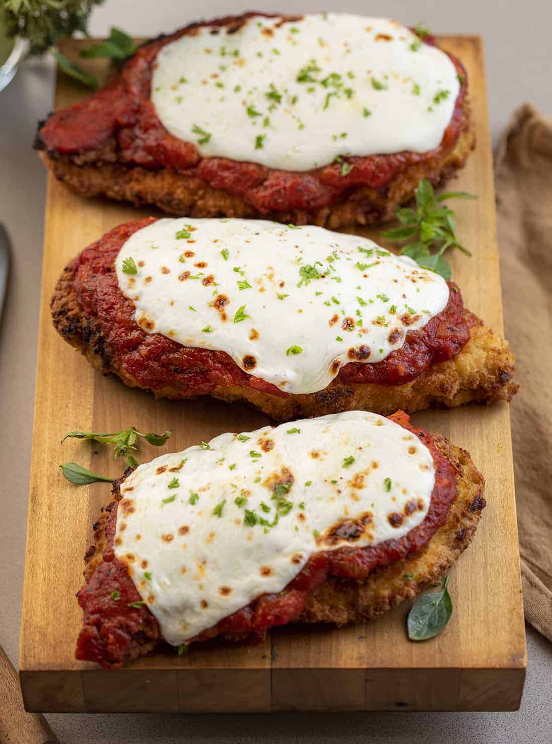 Three Chicken Parmesan on Cutting Board