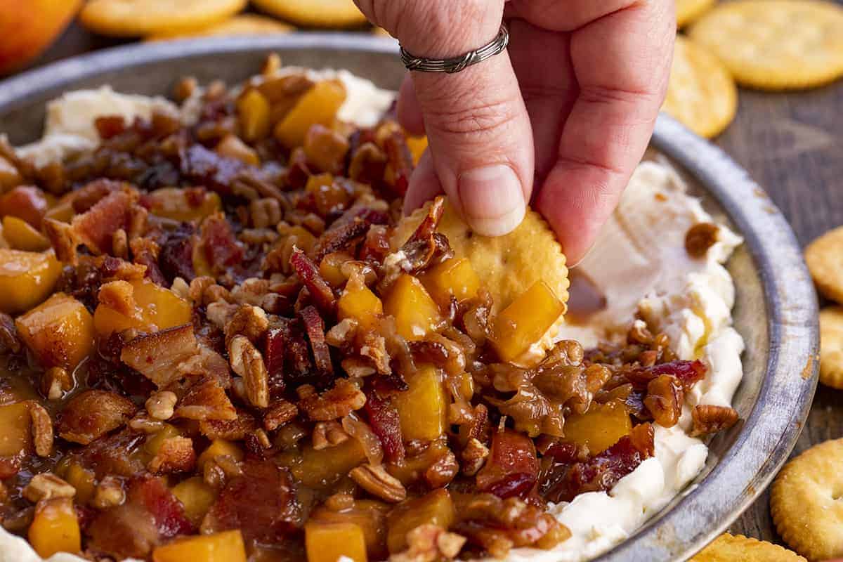 Hand Scooping up some Bourbon Peach Pecan Dip From Pan