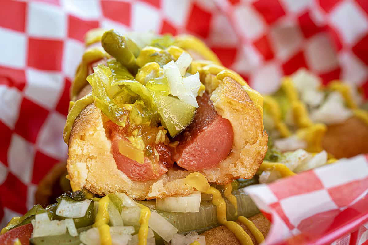 Chicago Style Corn Dog Cut in Half in a Basket with Another Chicago Style Corn Dog.