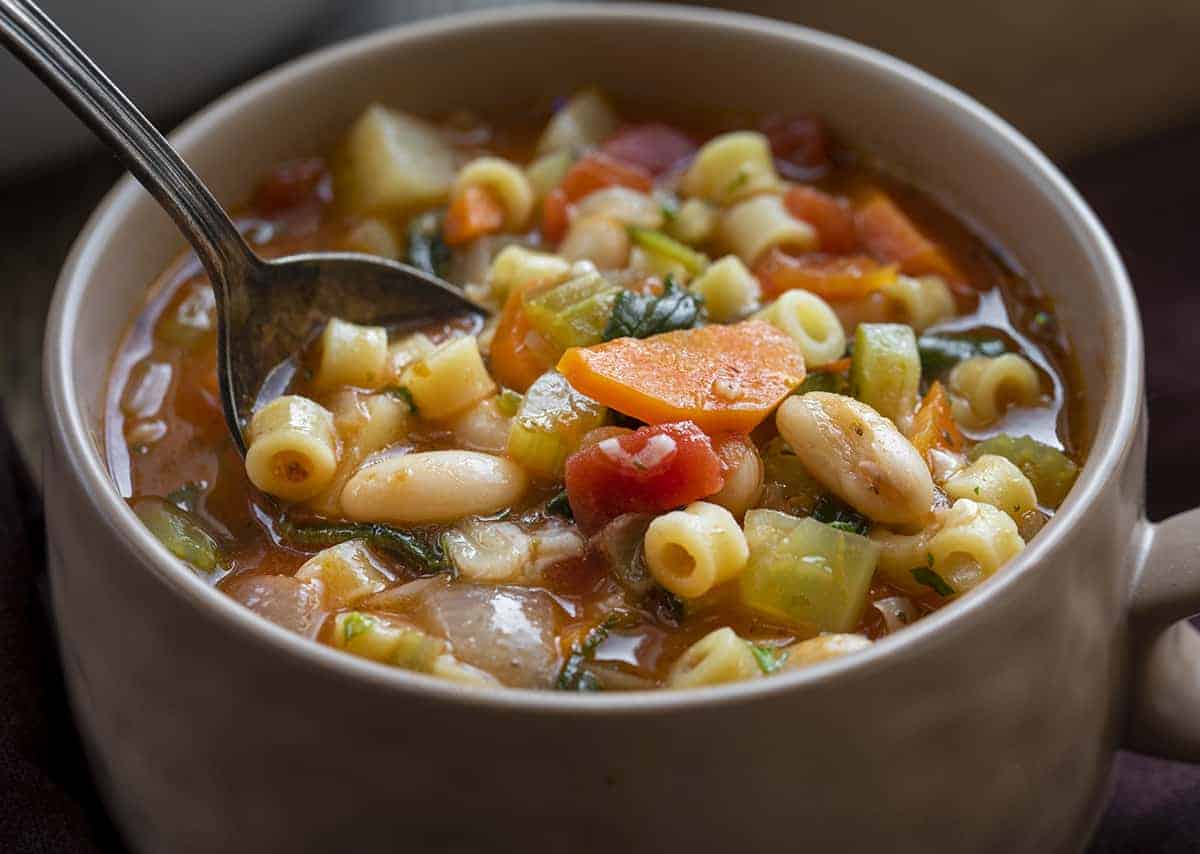 Bowl of Classic Minestrone Soup with a Spoon Taking a Bite