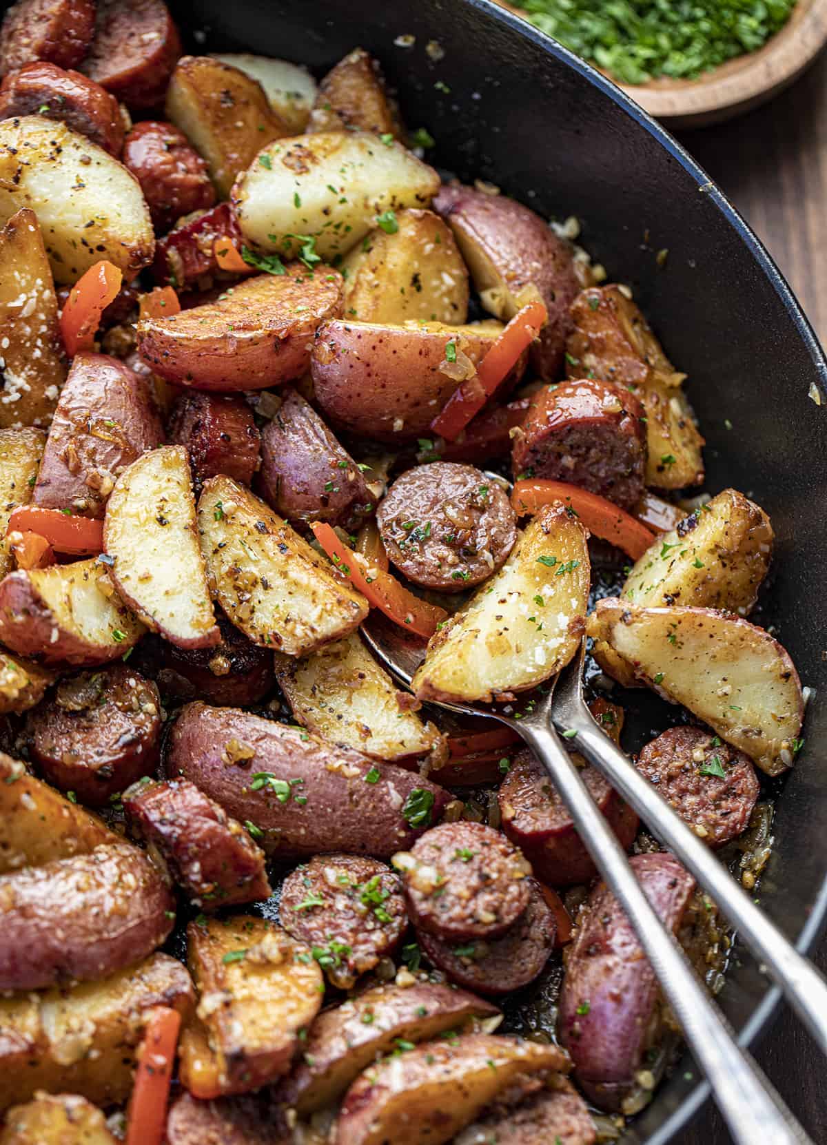 Close up of Kielbasa and Potatoes in a Pan with Spoons.