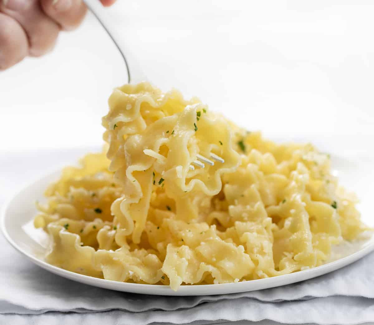 Fork Twirling Butter Noodles on a White Plate