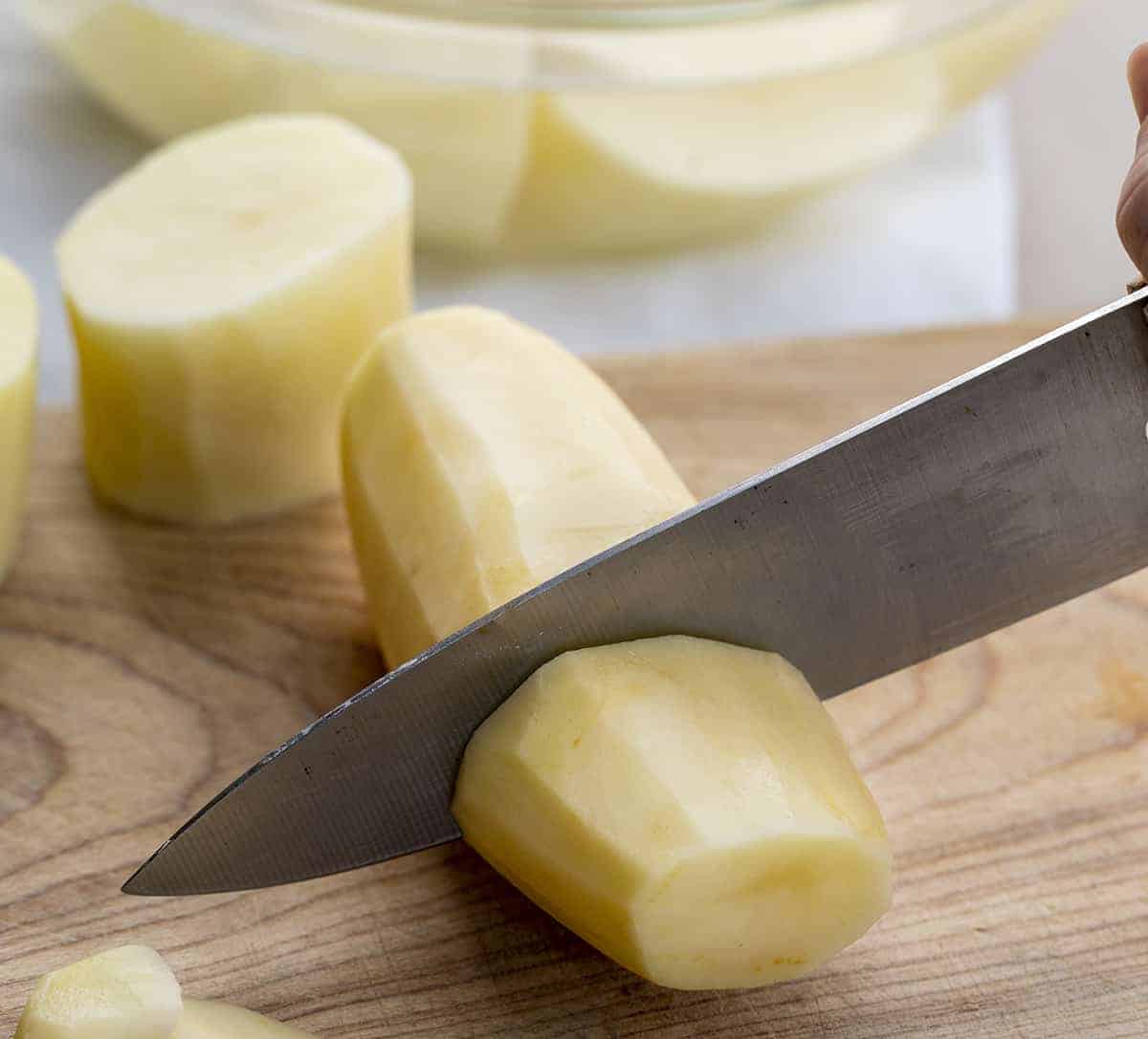 Knife cutting into a peeled potato for Fondant Potatoes