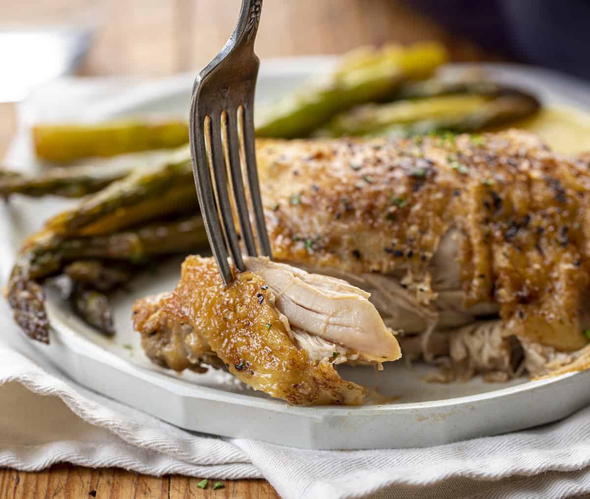 Fork with a Bite of Juicy Garlic Butter Chicken Thighs with Asparagus