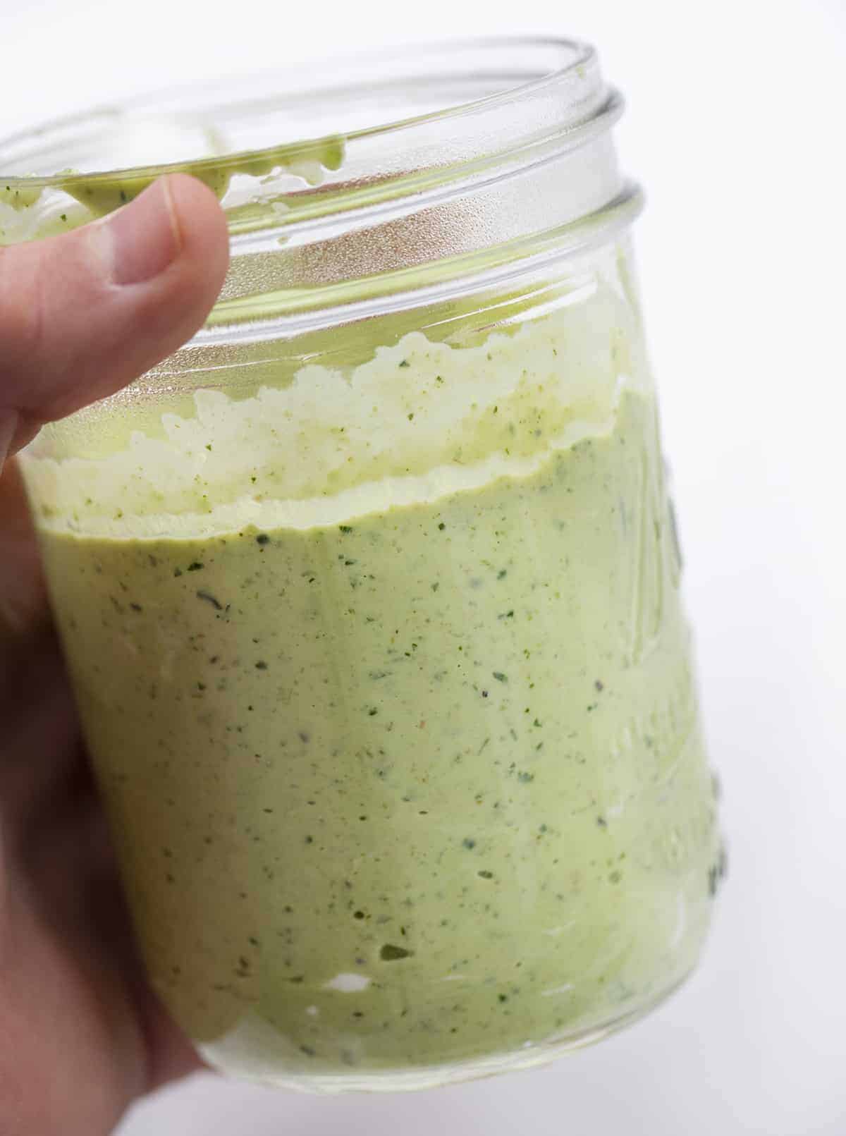 Hand Holding Jar of Avocado Sauce