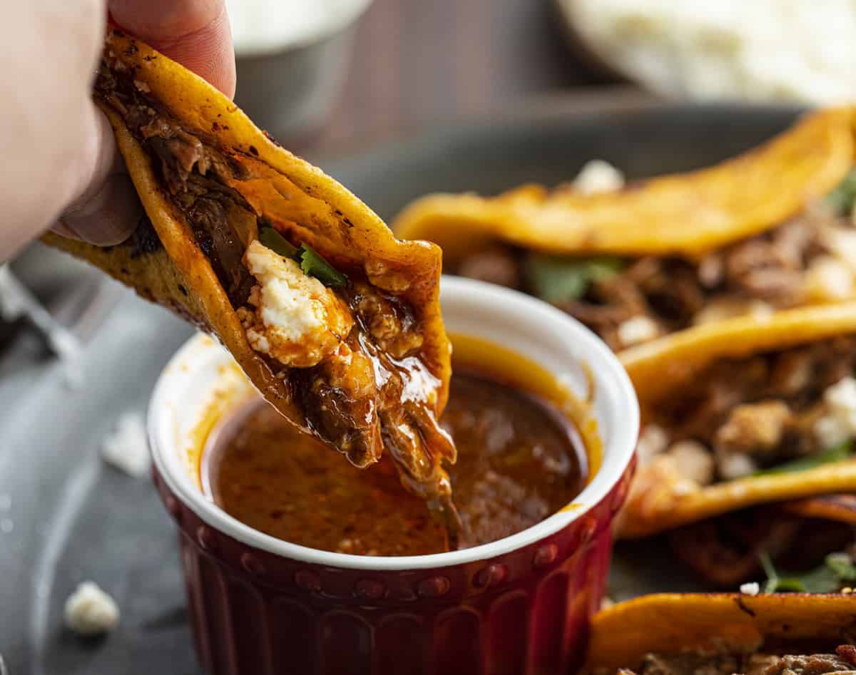 Dipping Slow Cooker Shredded Beef Tacos into the Sauce 