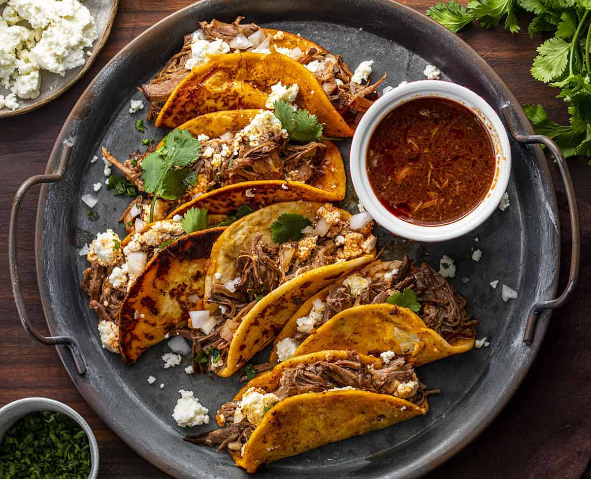 Platter of Slow Cooker Shredded Beef Tacos - Lazy Birria Tacos with Sauce and Queso Fresco 