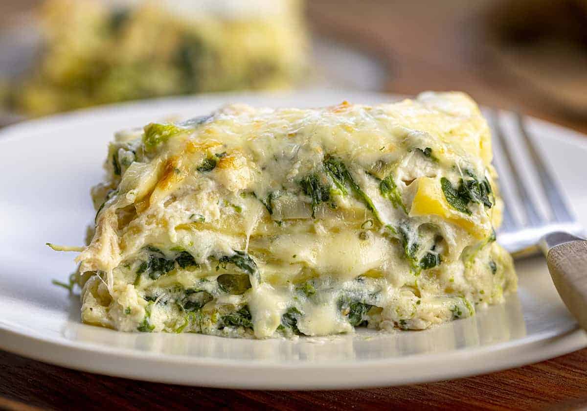 Piece of Cheesy Spinach and Artichoke Lasagna on a Plate with a Fork.
