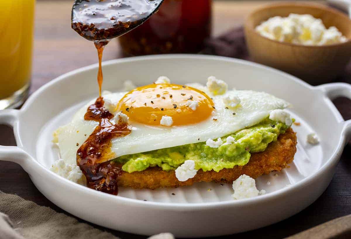 Adding Chili Sauce to Air Fryer Egg and Avocado Hash Brown Breakfast