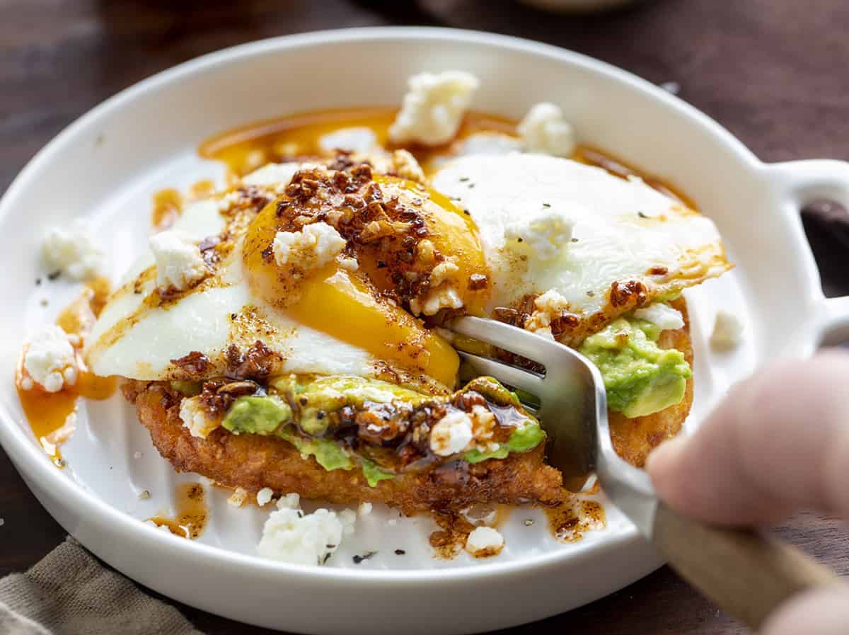 Fork Taking a Bite Out of Egg and Avocado Hash Brown Breakfast