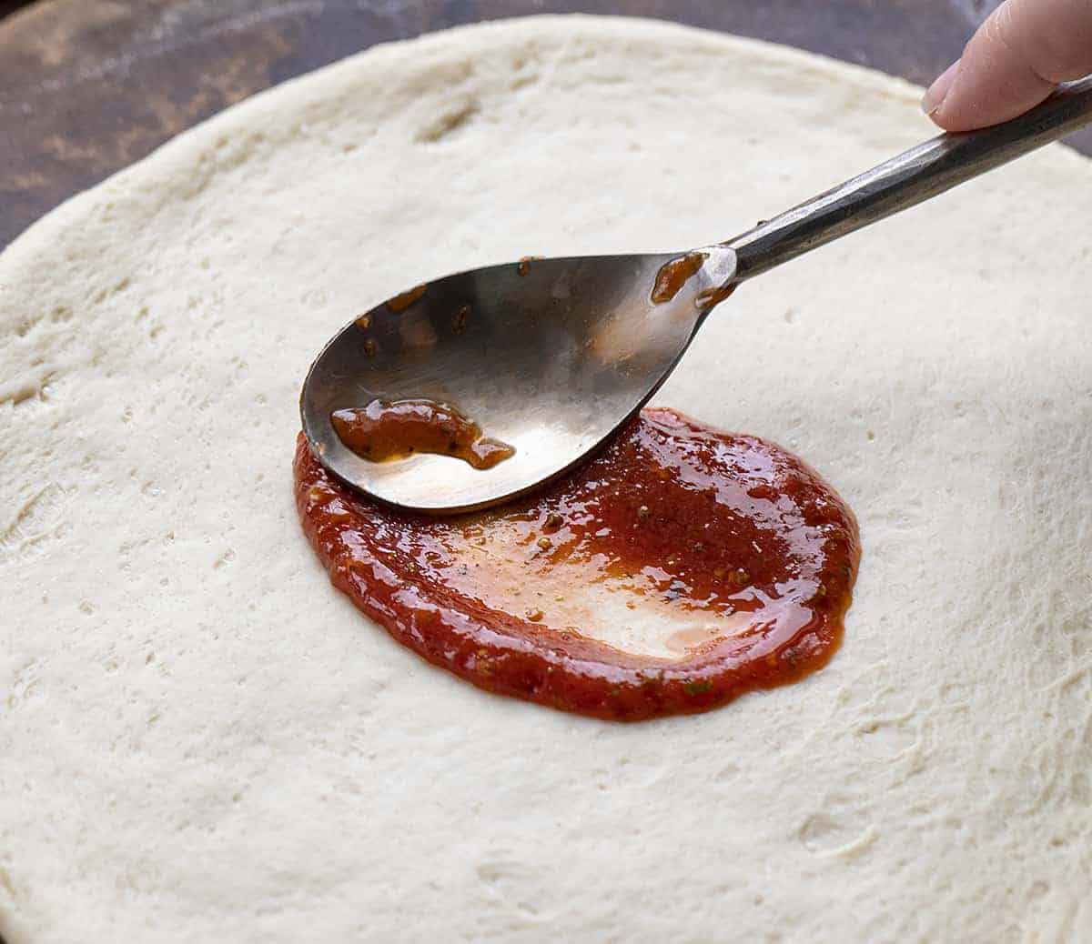 Spreading Pizza Sauce on a Raw Pizza Crust