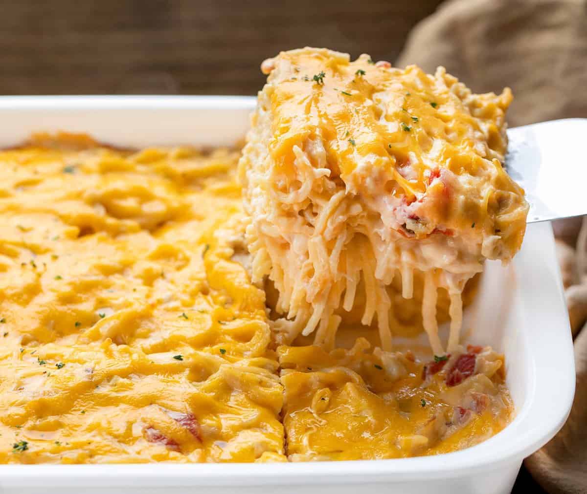 Scooping up a Piece of Chicken Spaghetti Mac and Cheese from Casserole Dish.