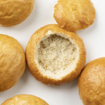 Bread Bowls on Counter With One Cut Open and Bread Removed From Inside.