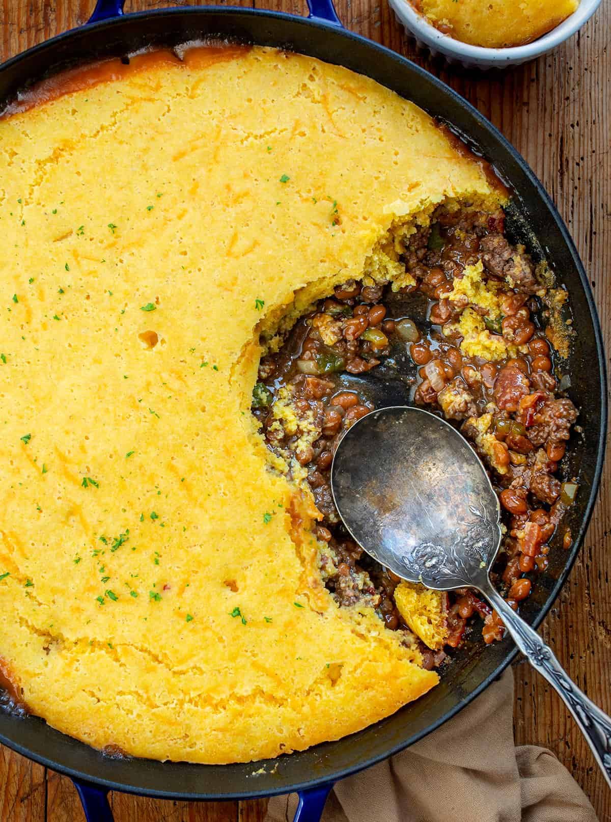 Cornbread Cowboy Casserole with Some Removed and Spoon in Pan from Overhead. 