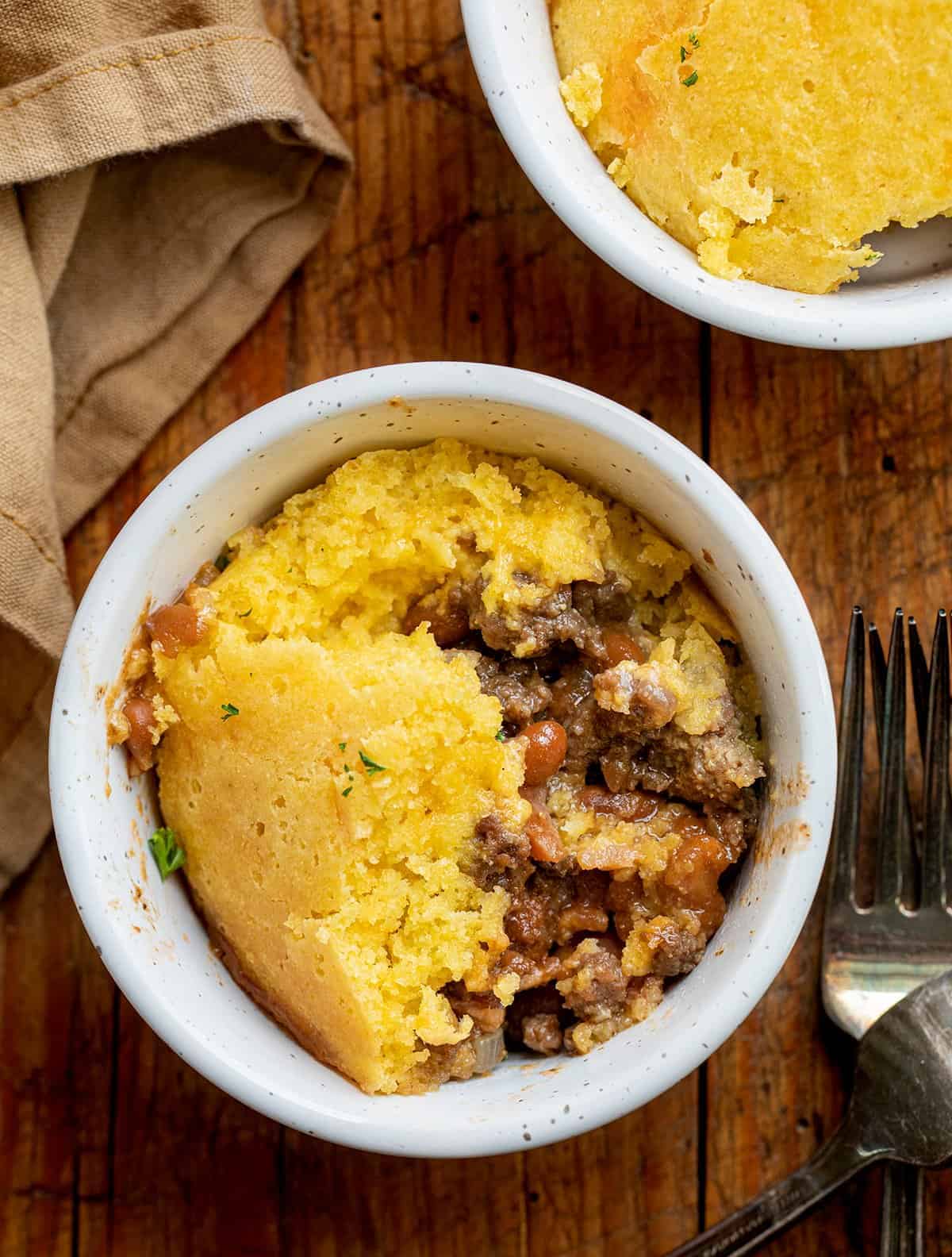 Two Bowls of Scooped Cornbread Cowboy Casserole and Forks from Overhead.