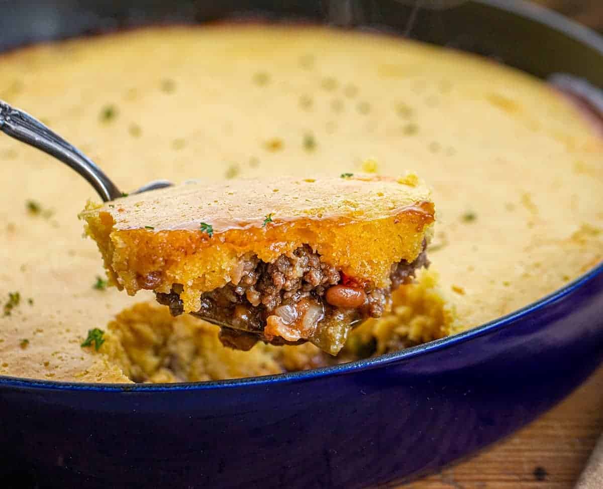 Scoop of Cornbread Cowboy Casserole in front of skillet.