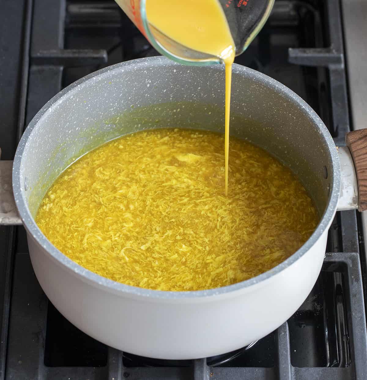 Pouring Eggs into Pot to Make Egg Drop Soup. Egg Drop Soup, Soup, Soup Recipes, Asian Soup, Asian Inspired Soup, Easy Egg Drop Soup, i am homesteader, iamhomesteader