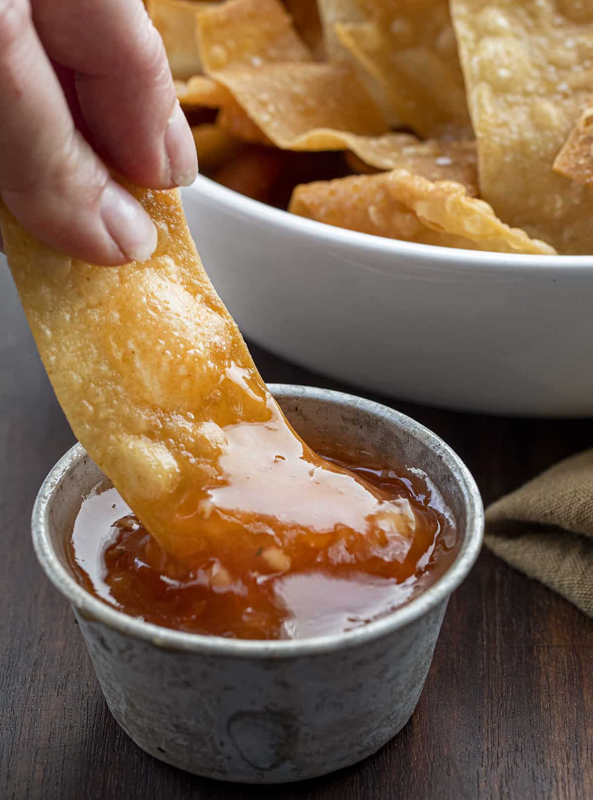 Dipping a Fried Wonton Chip into Sweet and Sour Suace. Wontons, Wonton Strips, Wonton Chips, Fried Wonton Chips, Oven Baked Wonton Chips, Crispy Wonton Chips, Fried Wontons, Asian Inspired Wonton Chips, recipes, i am homesteader, iamhomesteader