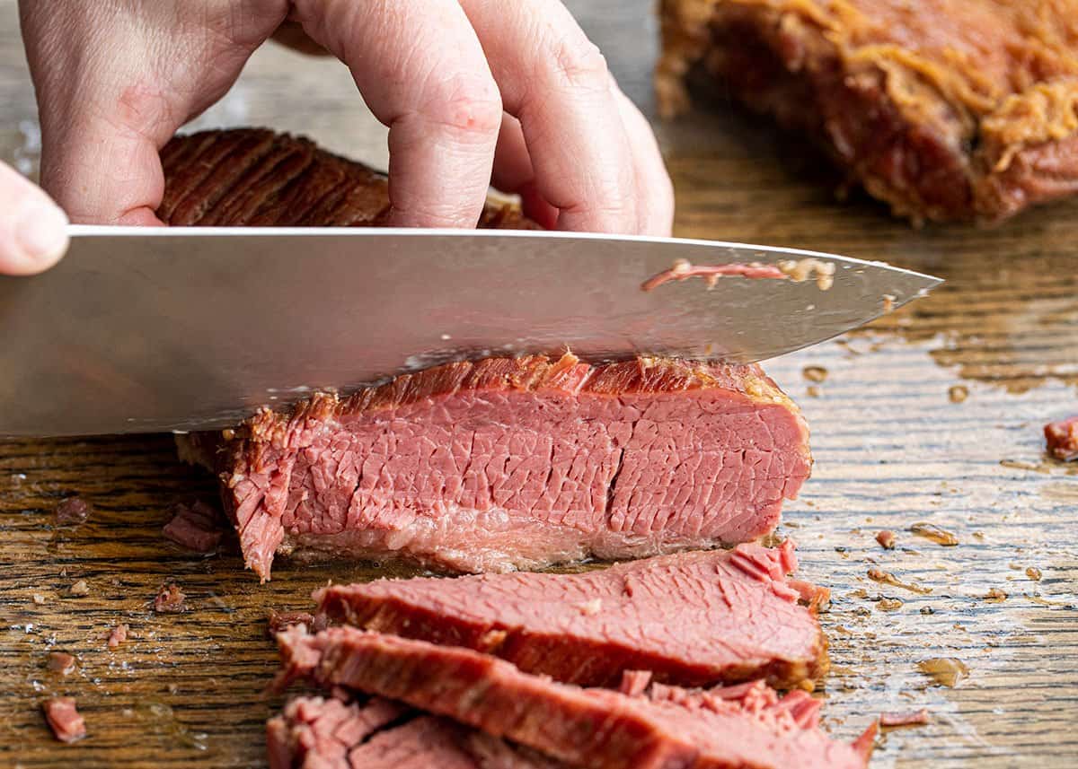 Hand Using Knife to Cut Corned Beef Slices