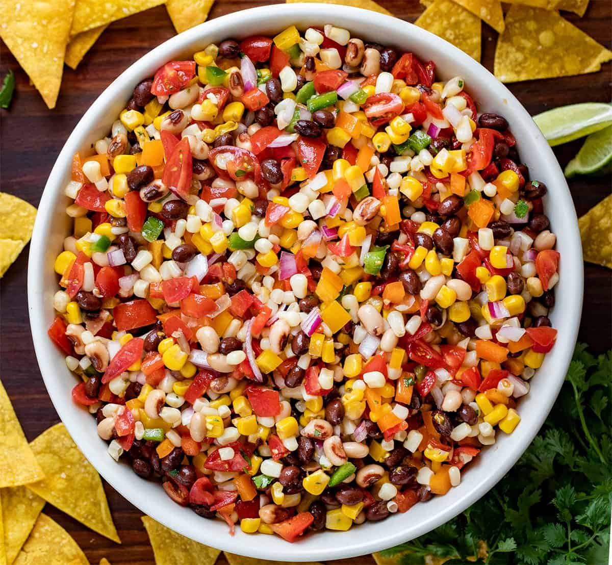 Bowl of Cowboy Caviar Recipe with Chips Around it on a Cutting Board. 